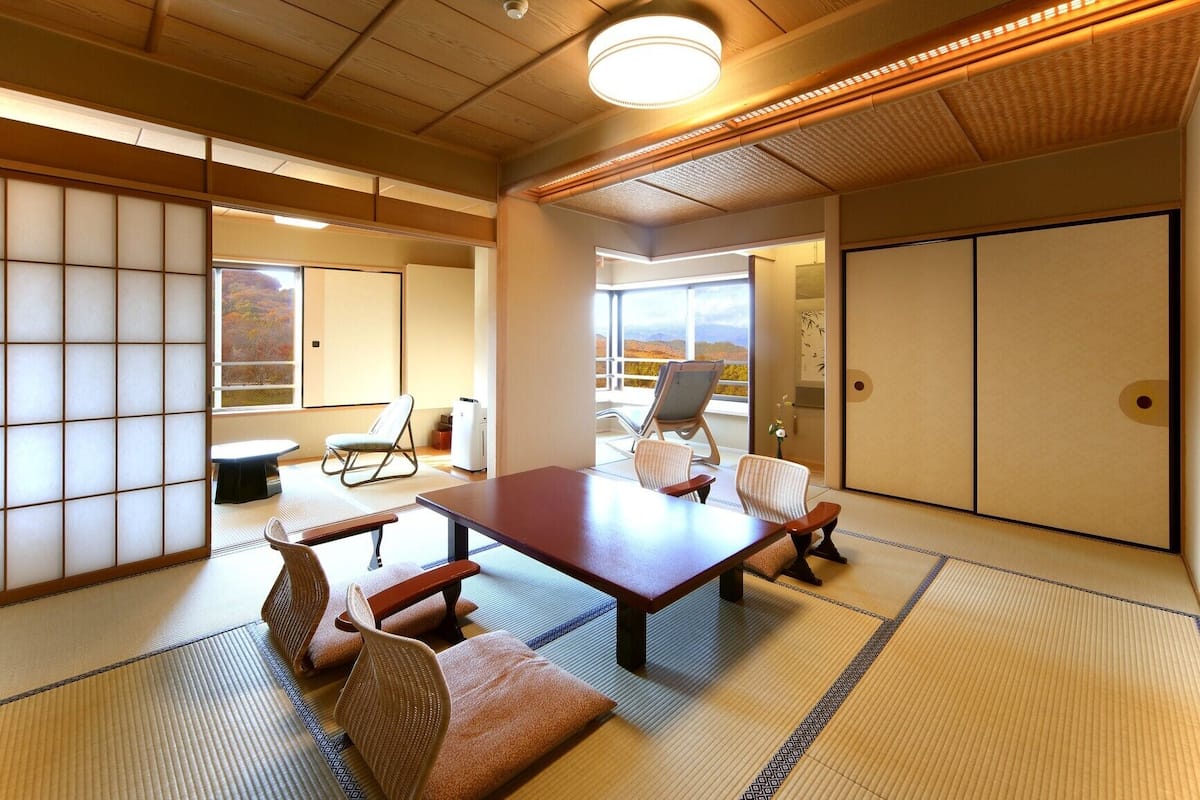 Una habitación japonesa tradicional con suelo de tatami, una mesa baja y asientos.