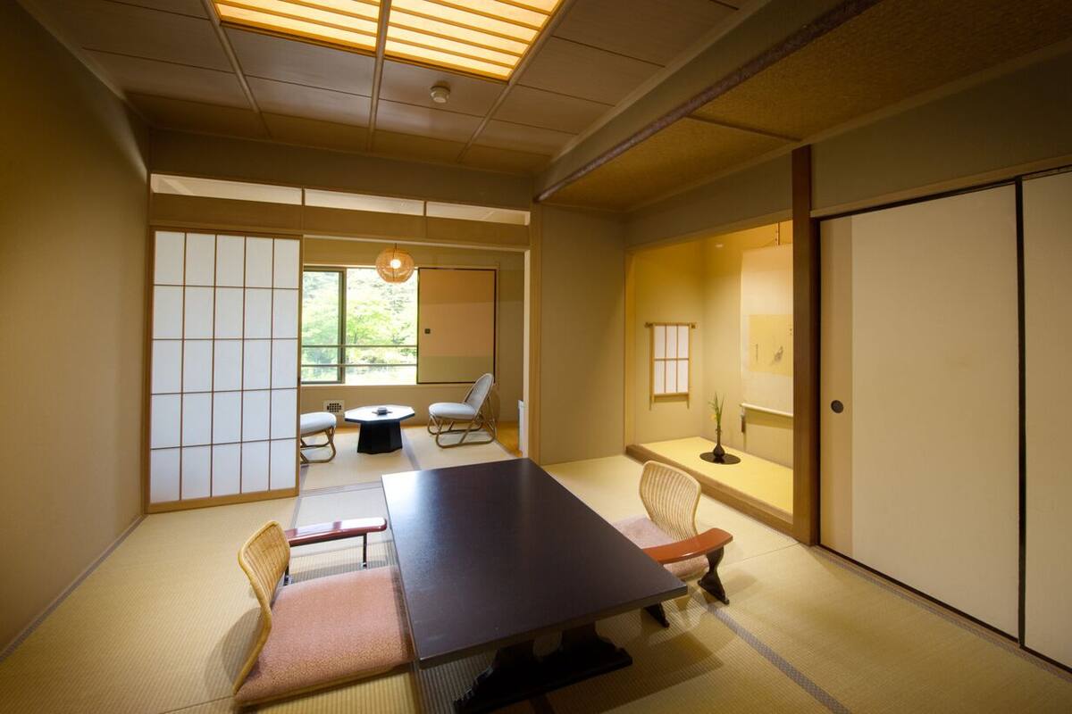 Una habitación japonesa tradicional con suelo de tatami, una mesa baja y puertas correderas.
