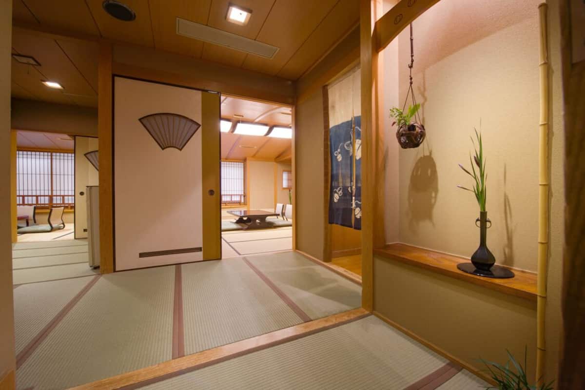 Una habitación japonesa tradicional con suelo de tatami, puerta corredera shoji y una planta colgante.