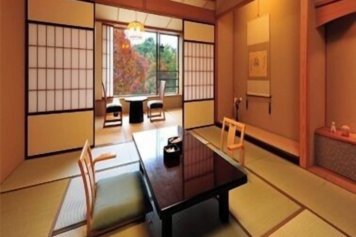 Una habitación tradicional japonesa con suelo de tatami, una mesa baja y puertas correderas.