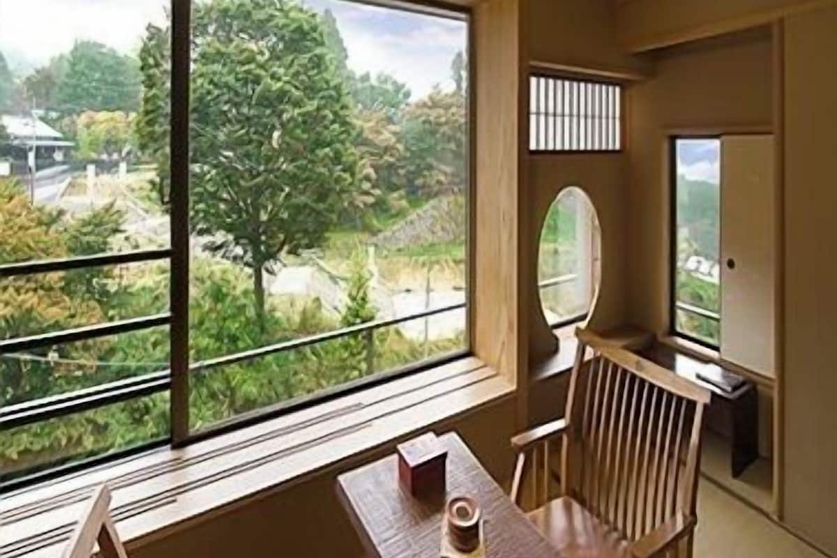 Una habitación con un ventanal grande, una mesa y una silla.