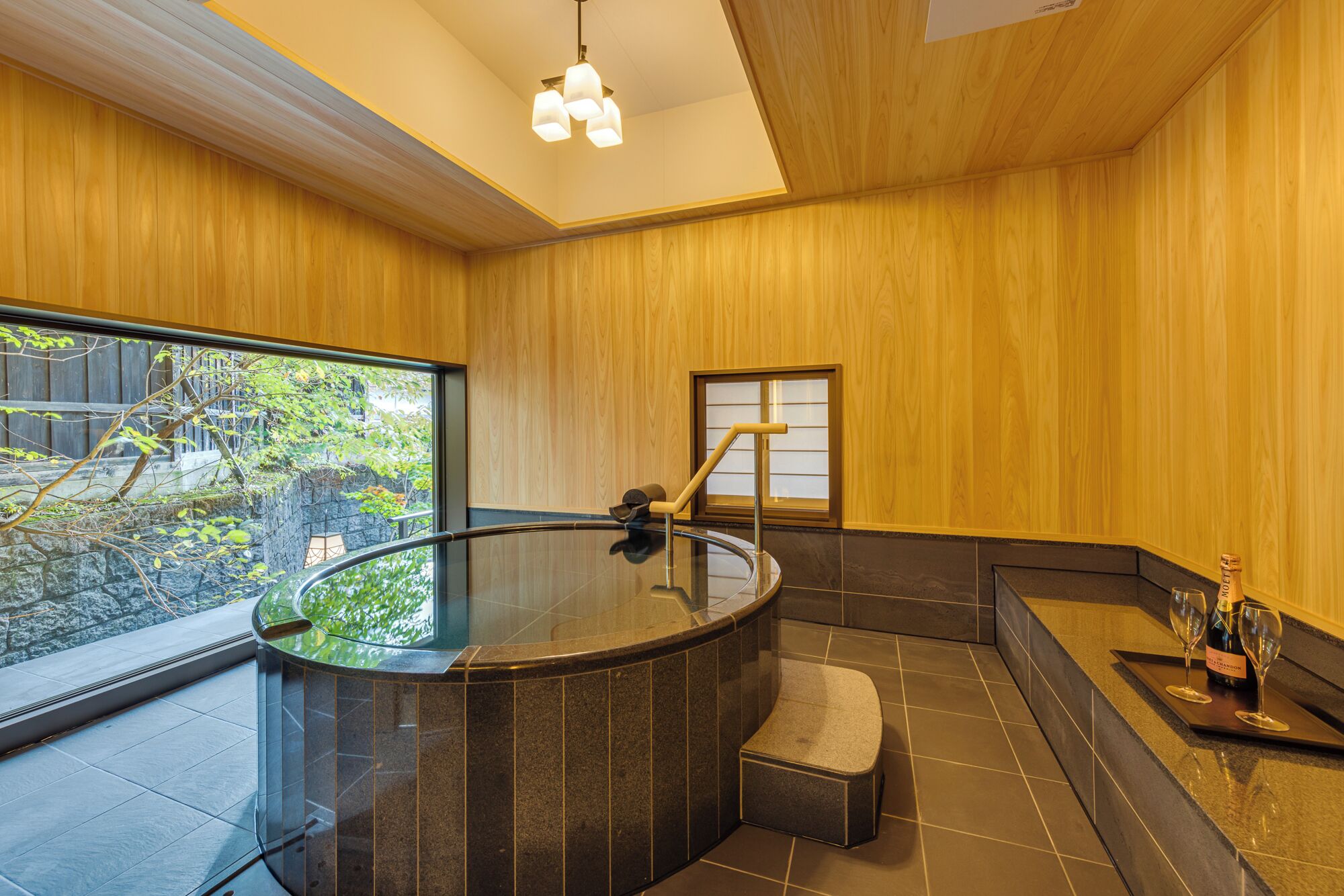 A modern bathroom with a glass-enclosed hot tub, a wooden interior, and a view of greenery outside.