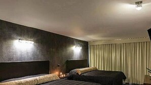 A hotel room with two beds, dark wood flooring, and a large window with curtains. - Suites Meson del Cid (Xalapa)