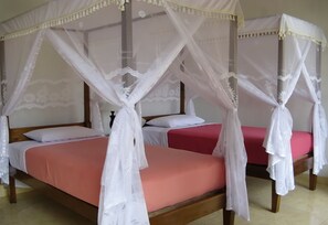 A four-poster bed with white canopy and red bedding.