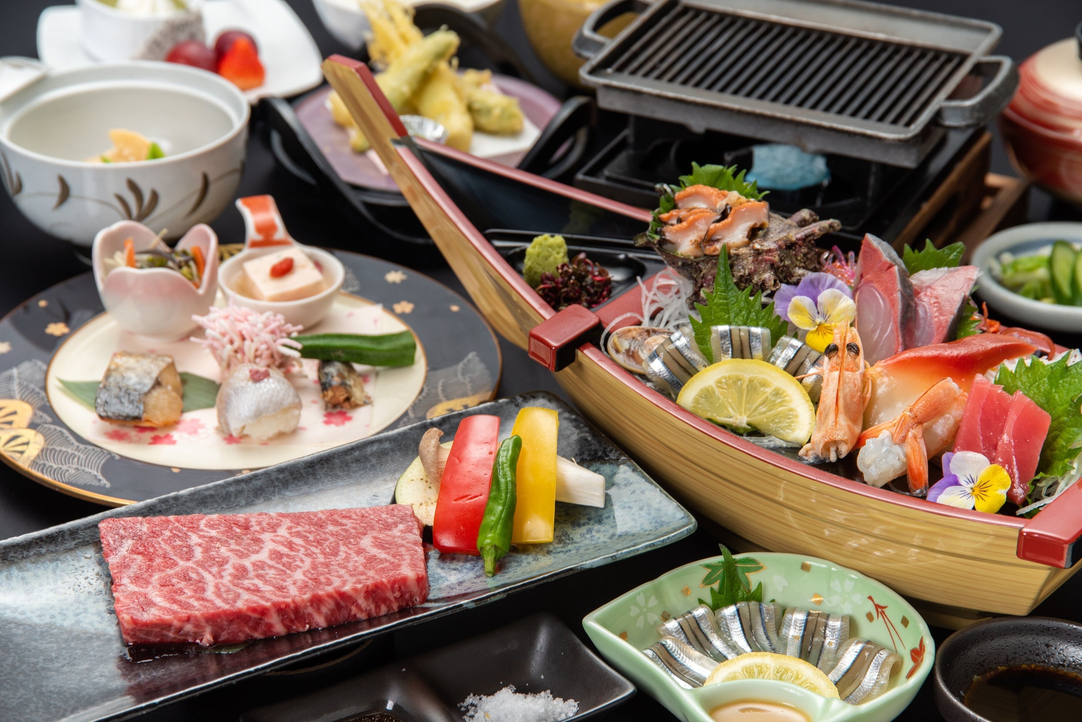 Une variété de plats de sushis et de sashimis sont disposés sur une table, notamment un grand plat en forme de bateau contenant des fruits de mer et des légumes.