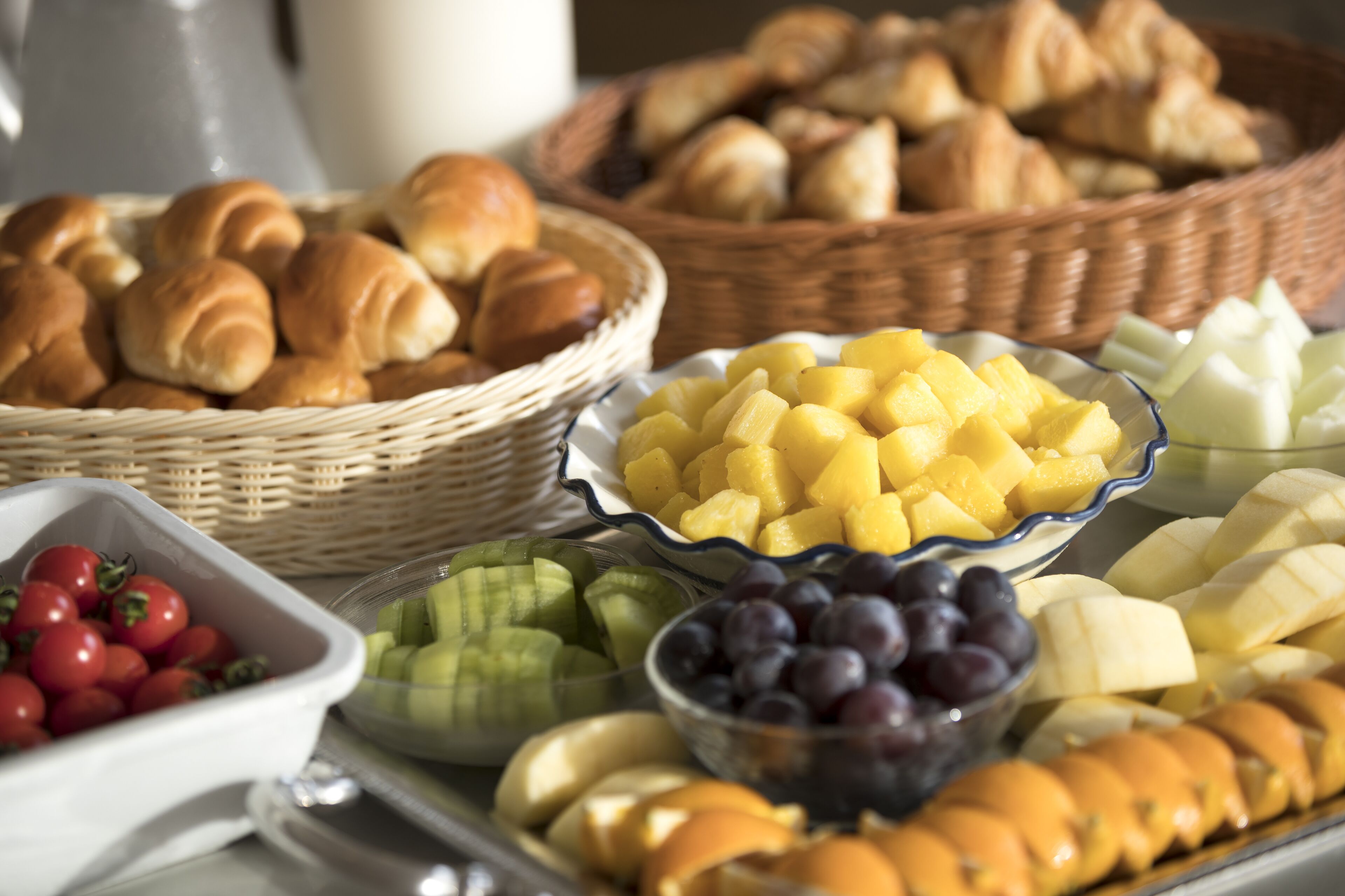 Un bufé de desayuno con frutas, quesos y productos de pastelería variados.