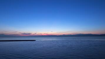 A calm sea at sunset with a clear sky.
