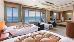 Una habitación de hotel con dos camas, una zona de estar y vista al mar.