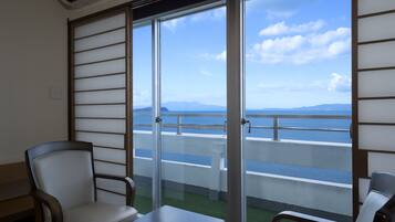 Balcón con vista al mar y a las montañas, con dos sillas y una mesa.