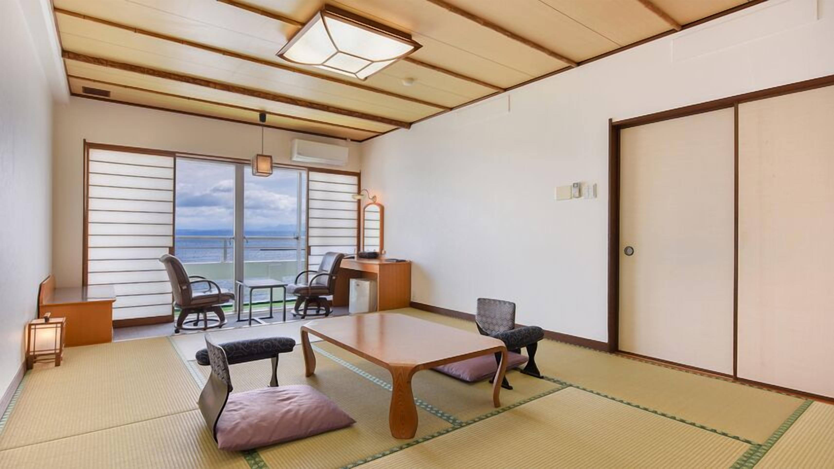 A room with tatami flooring, a low table, chairs, a view through large windows, and a sliding door.