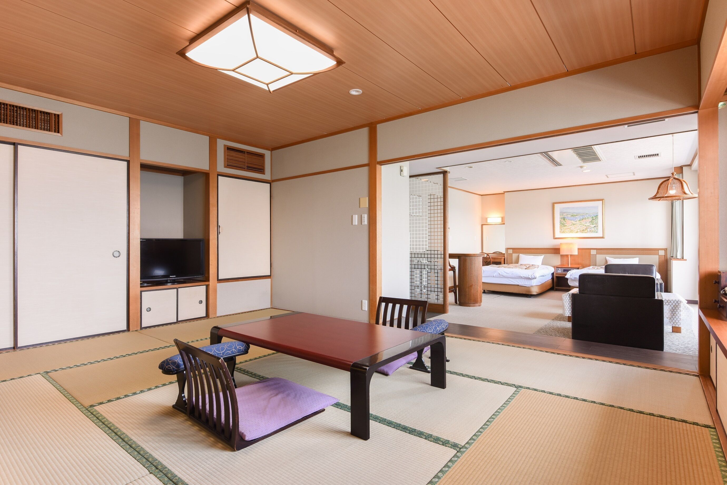 A traditional Japanese-style room with tatami flooring, a low table, and a television.