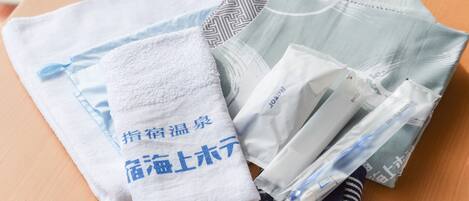 A neatly folded set of towels and a striped sock on a wooden surface.