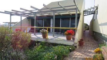 A covered outdoor area with a pergola, potted plants, and a brick pathway.