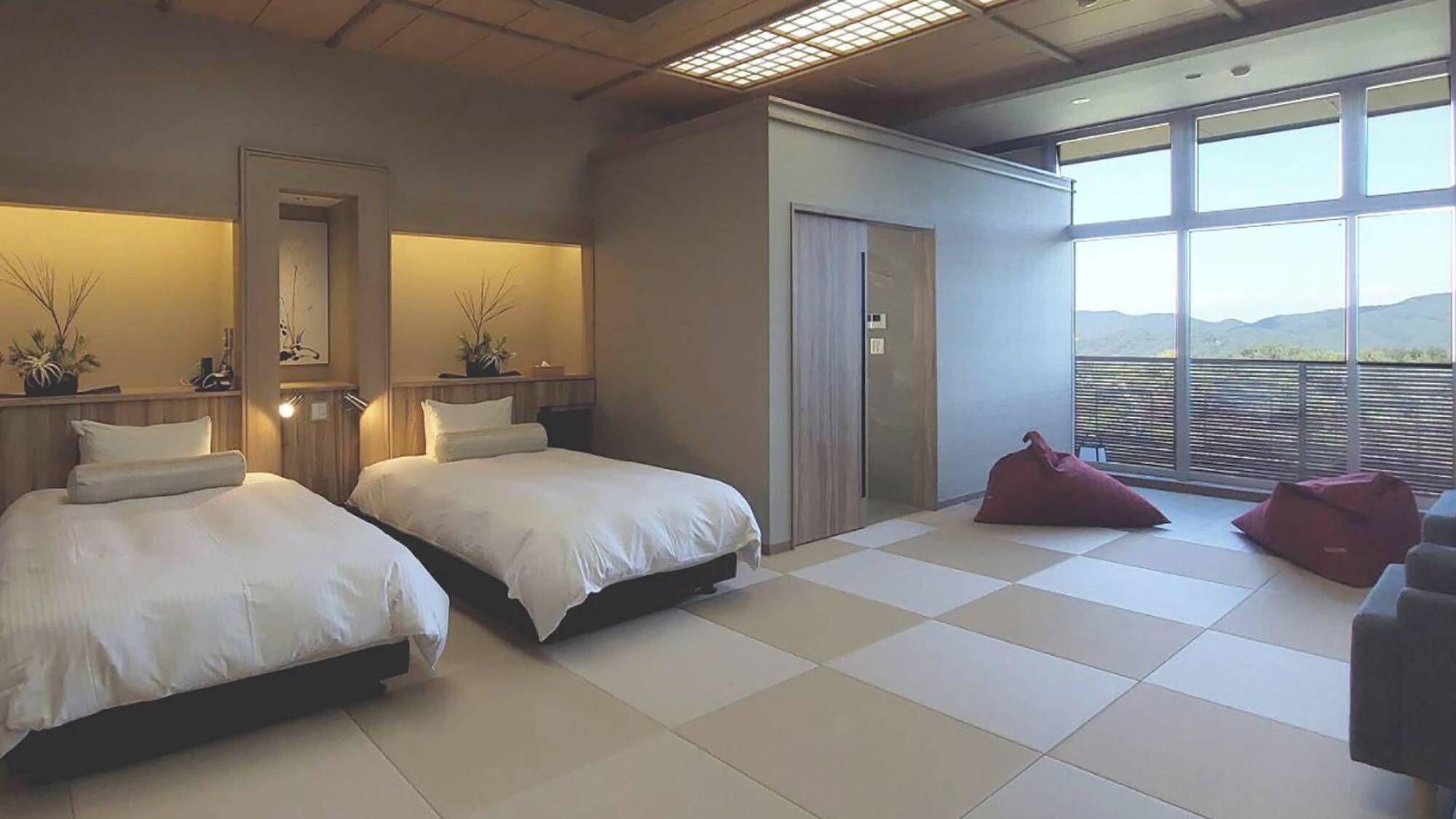 A hotel room with two beds, a large window with a view, and a balcony.