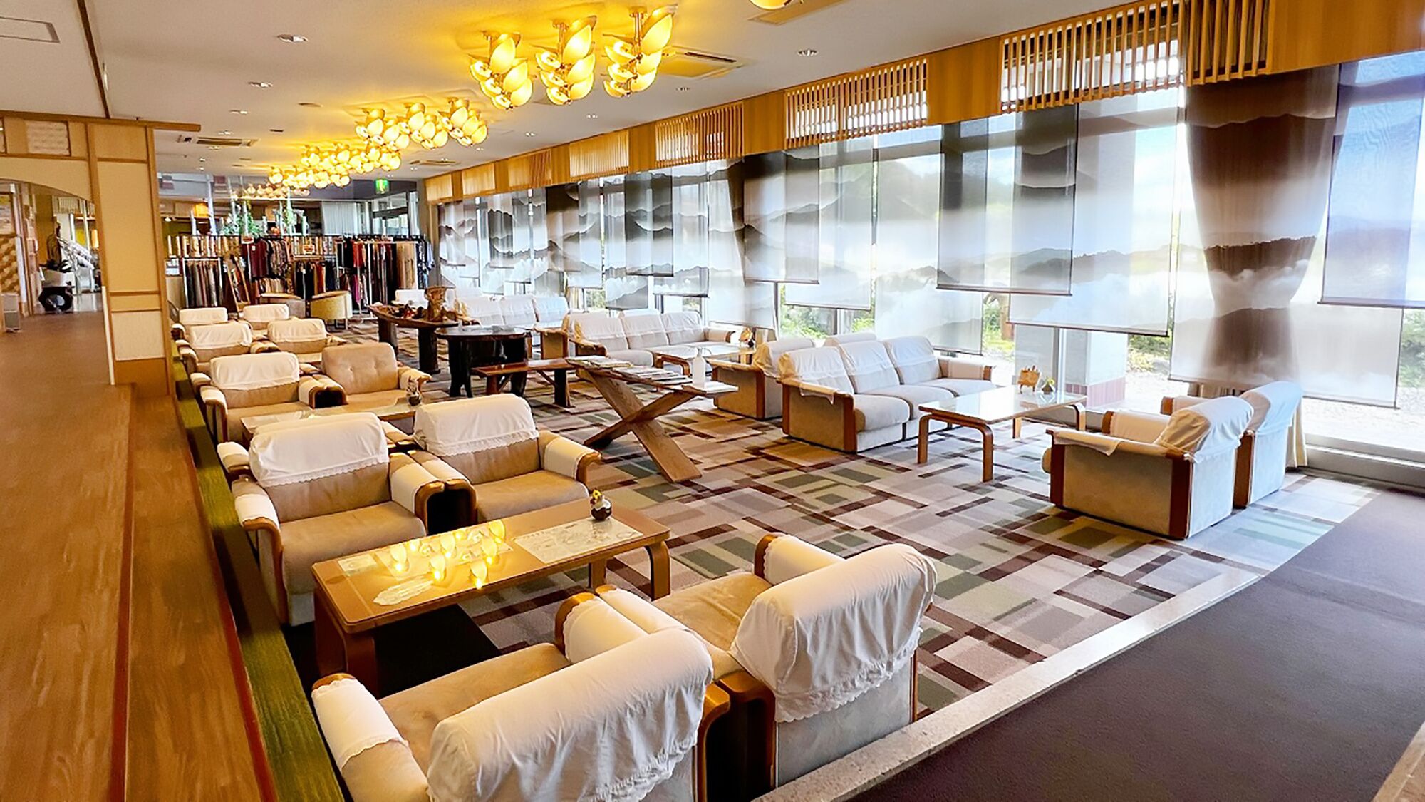 Un vestíbulo de hotel con zonas de estar, una mesa de recepción y grandes ventanales.