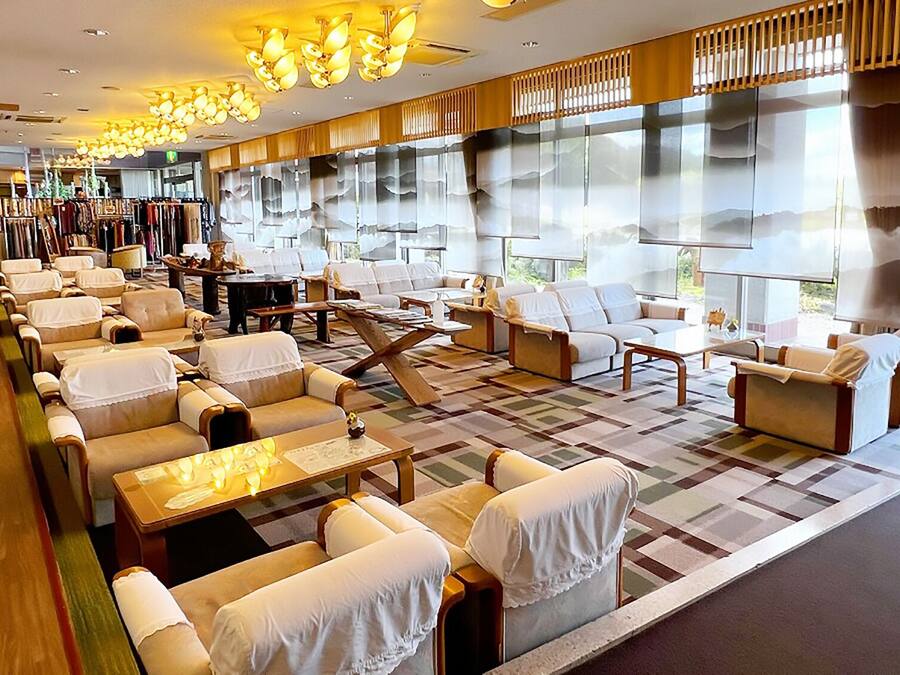 Un vestíbulo de hotel con zonas de estar, una mesa de recepción y grandes ventanales.