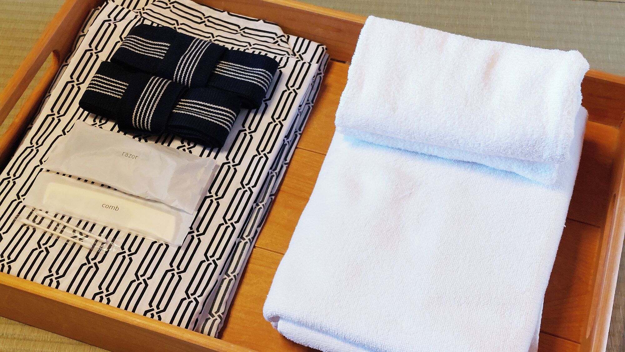 A wooden tray with a patterned cloth, a folded white towel, and a comb.