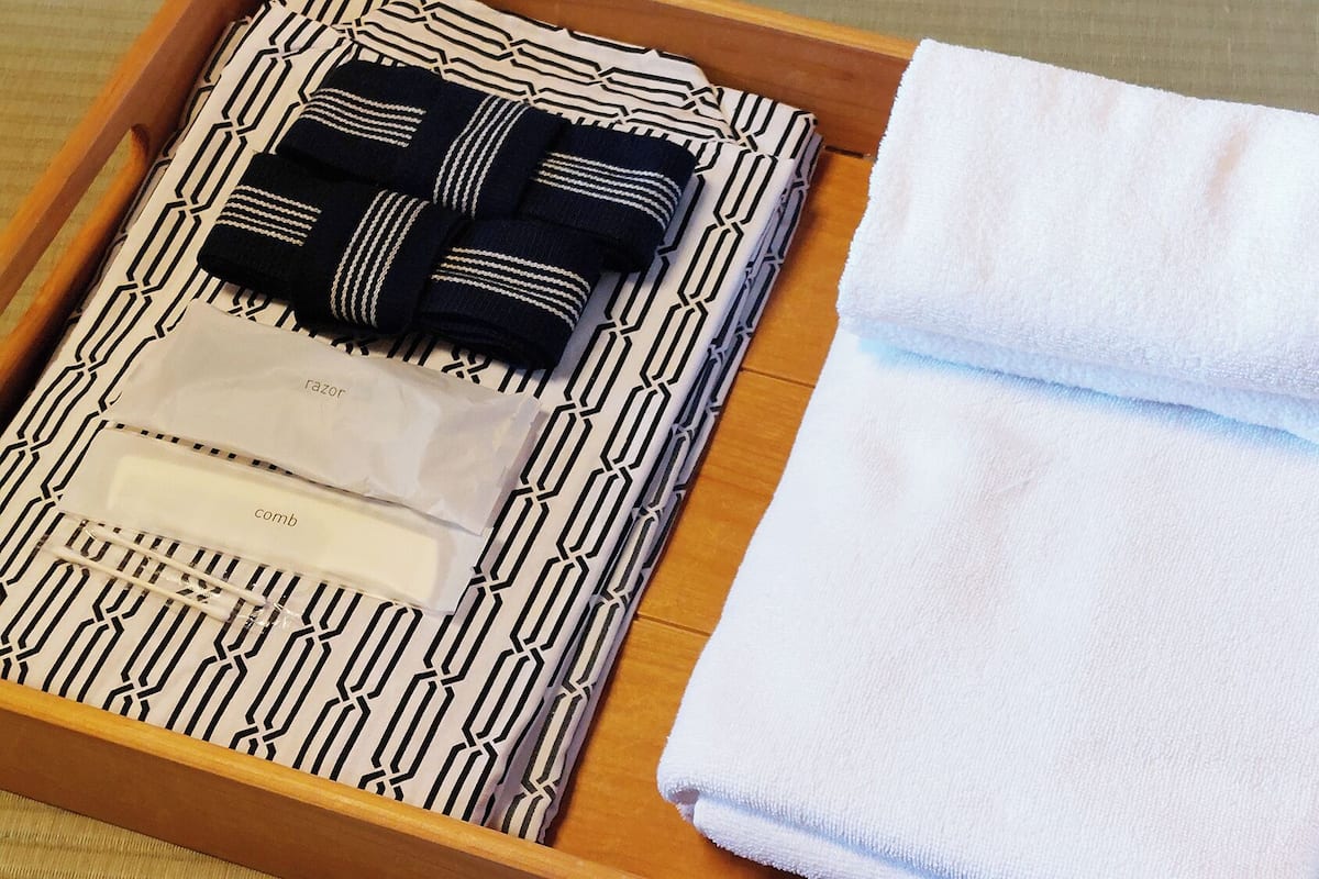 A wooden tray with a patterned cloth, a folded white towel, and a comb.