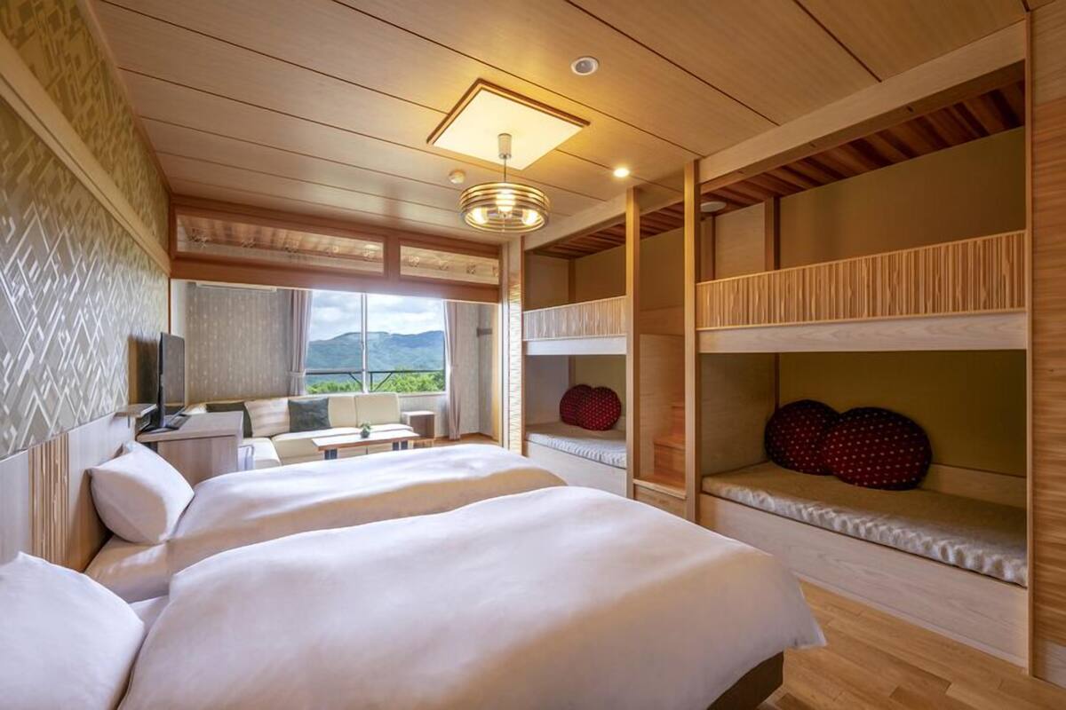 Una habitación de hotel con una cama grande, una cama individual, un escritorio y vistas a las montañas.
