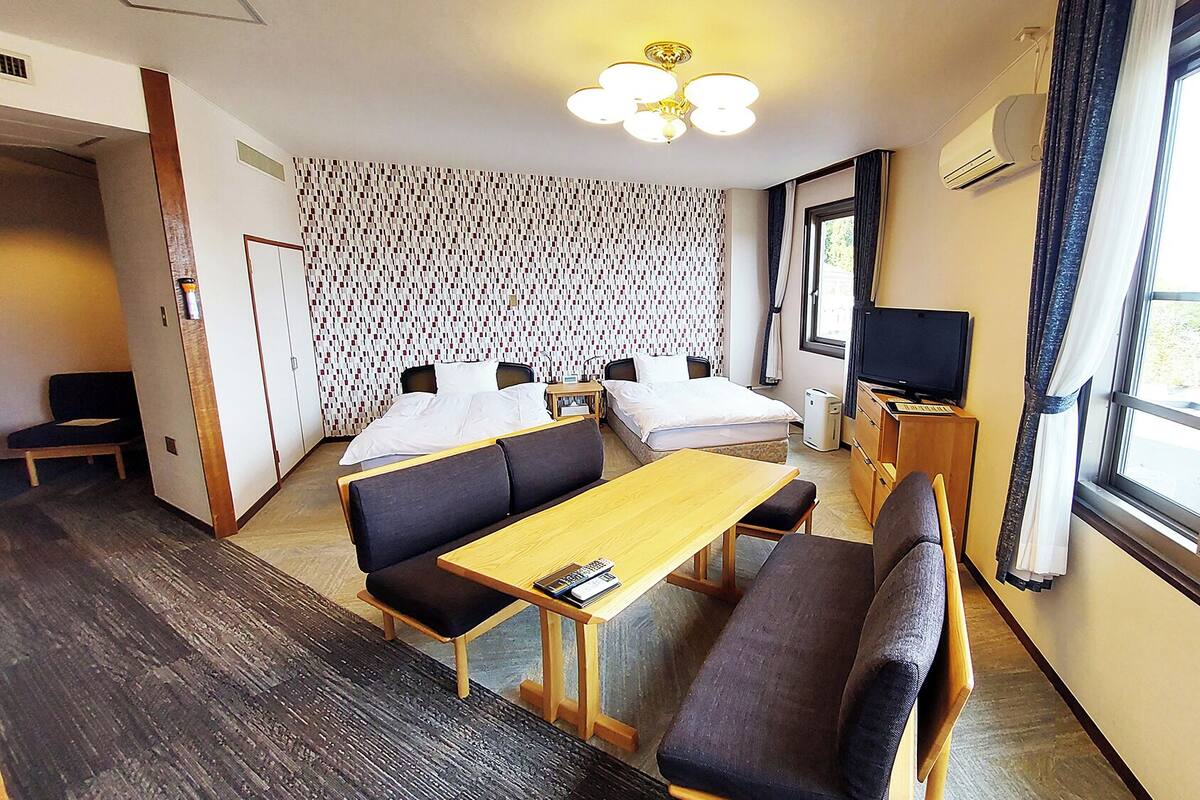 Habitación de hotel con cama, sofá, mesa, televisión y pared con diseño.