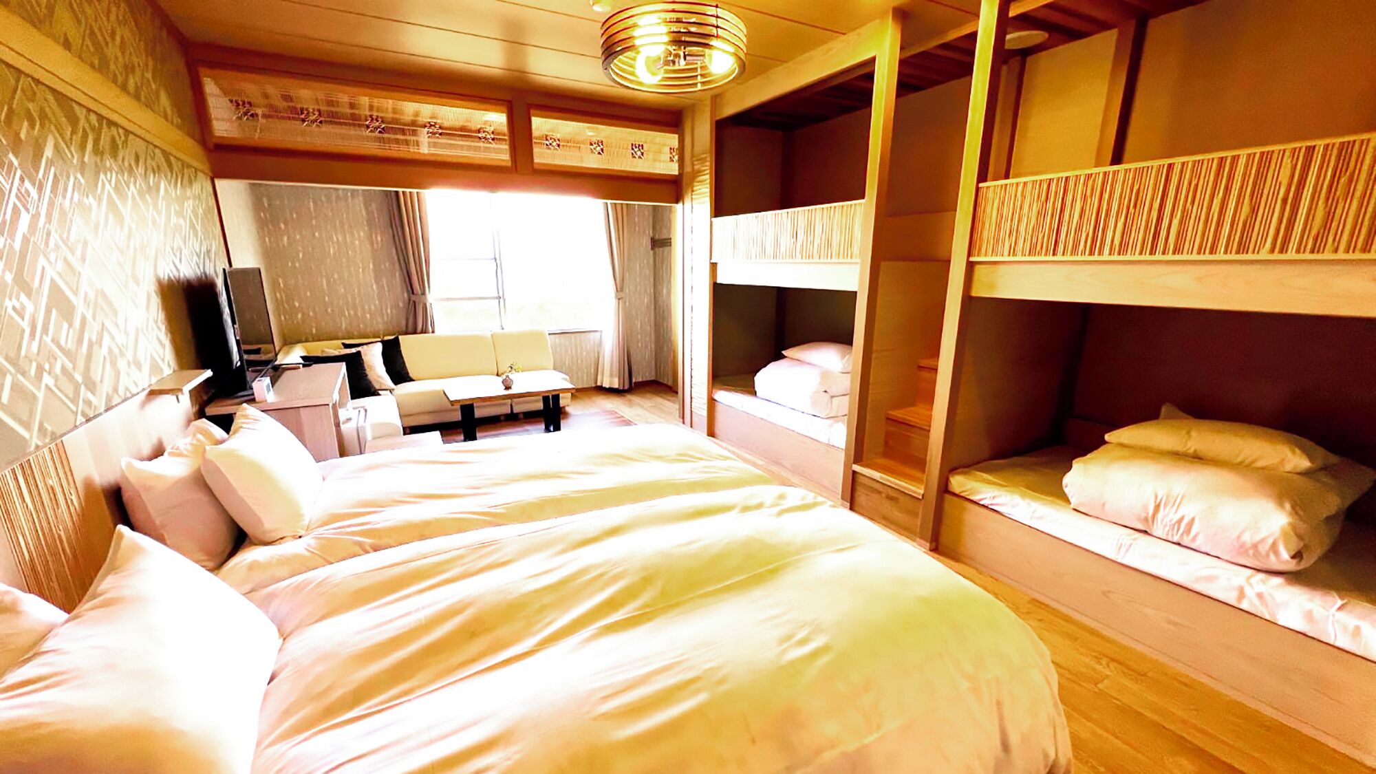 A room with bunk beds, a desk, a chair, and a television.