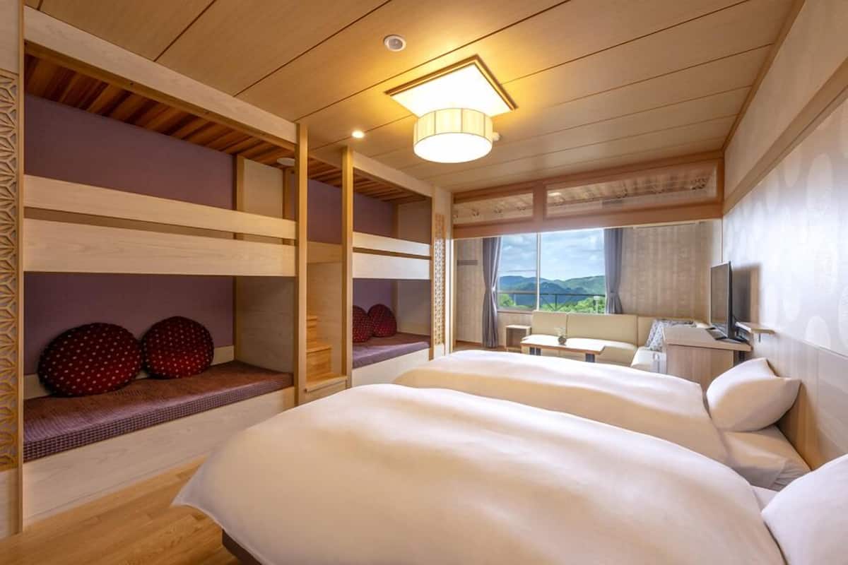 A room with bunk beds, a desk, a chair, and a window with a view.