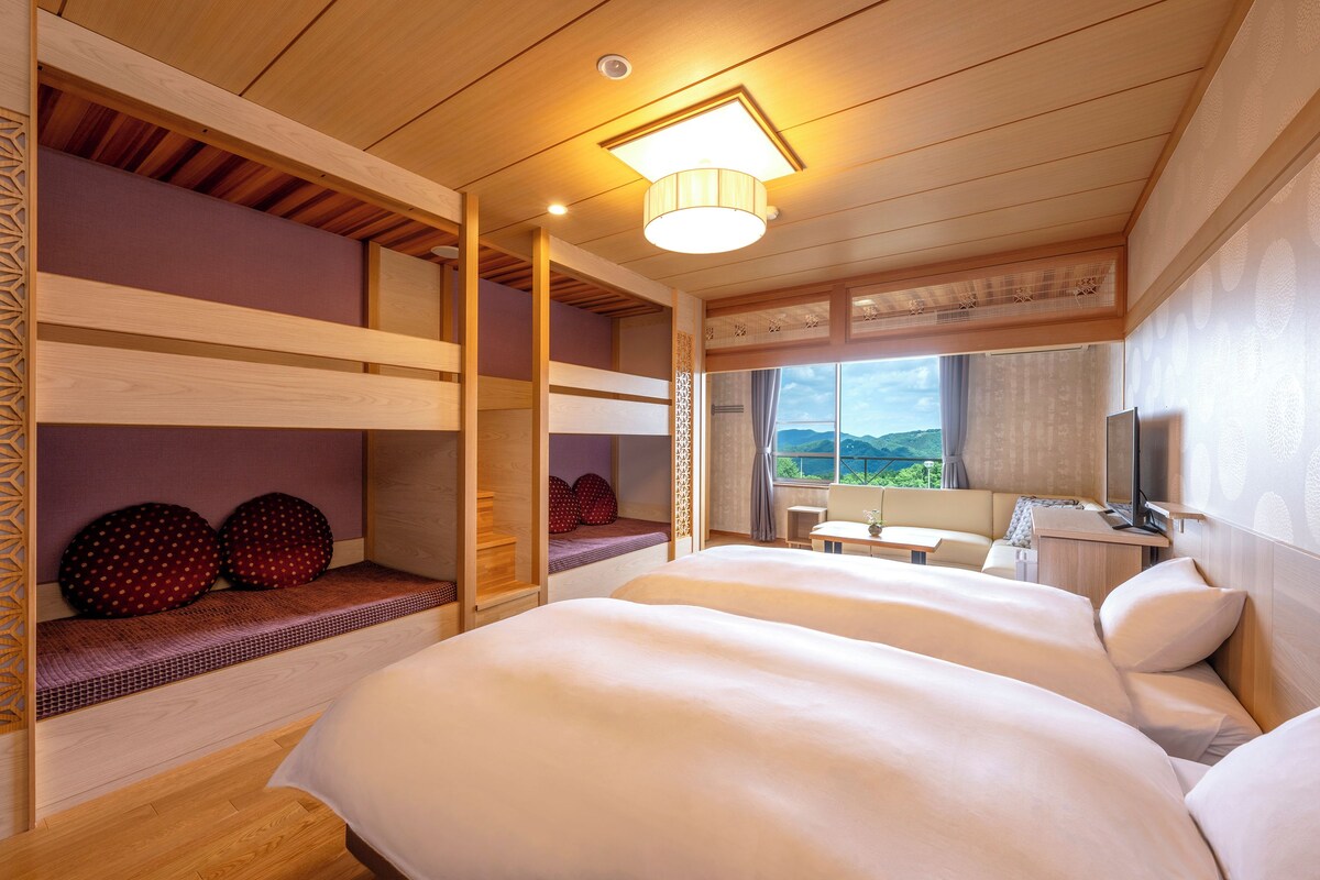 A hotel room with bunk beds, a desk, and a large window with a mountain view.