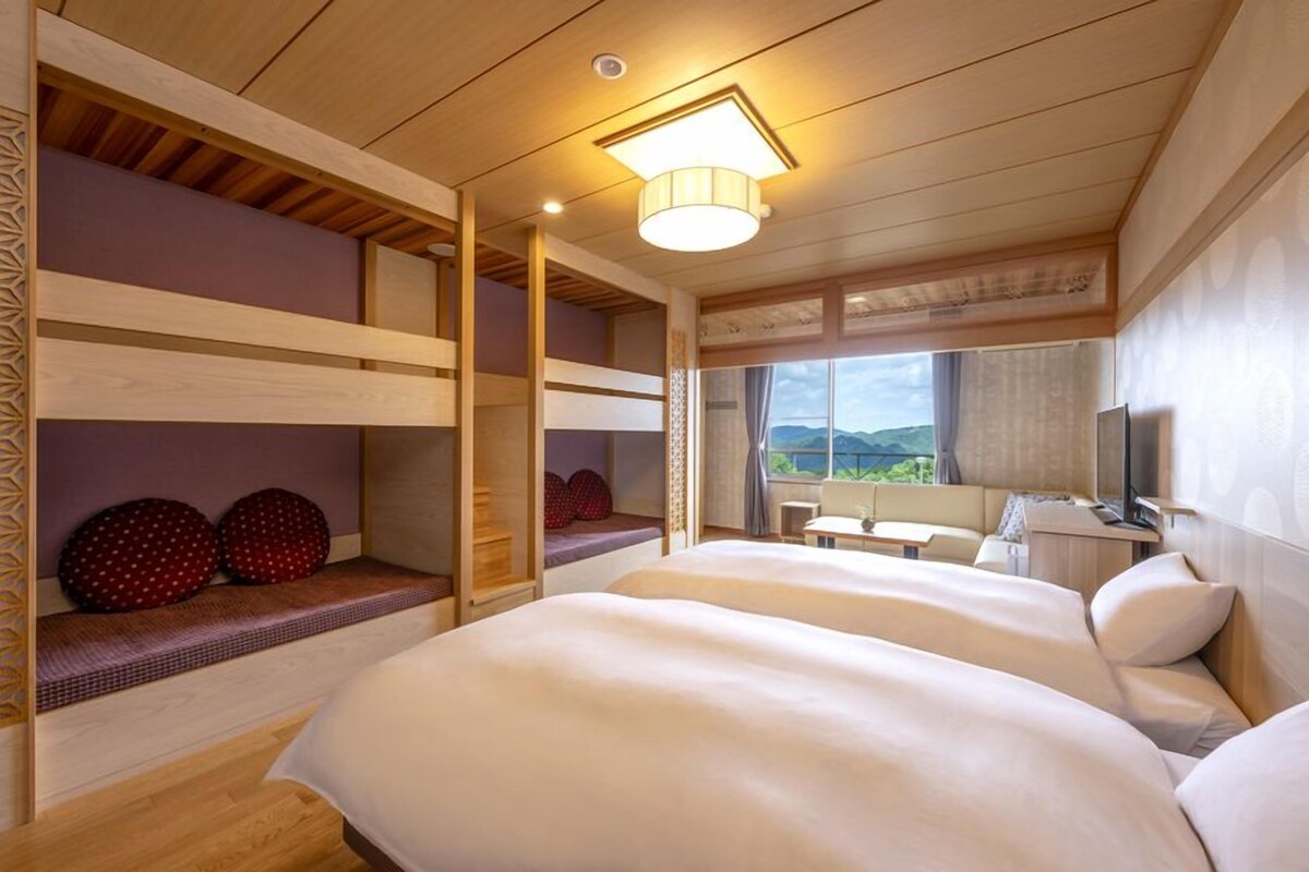 Une chambre avec des lits superposés, un bureau, une chaise et une fenêtre donnant sur un paysage agréable.