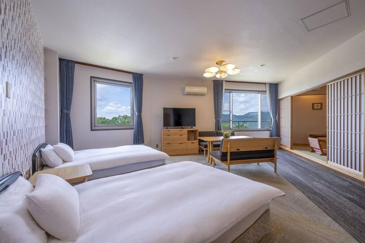 Habitación de hotel con dos camas, un escritorio, un televisor y vistas al exterior.