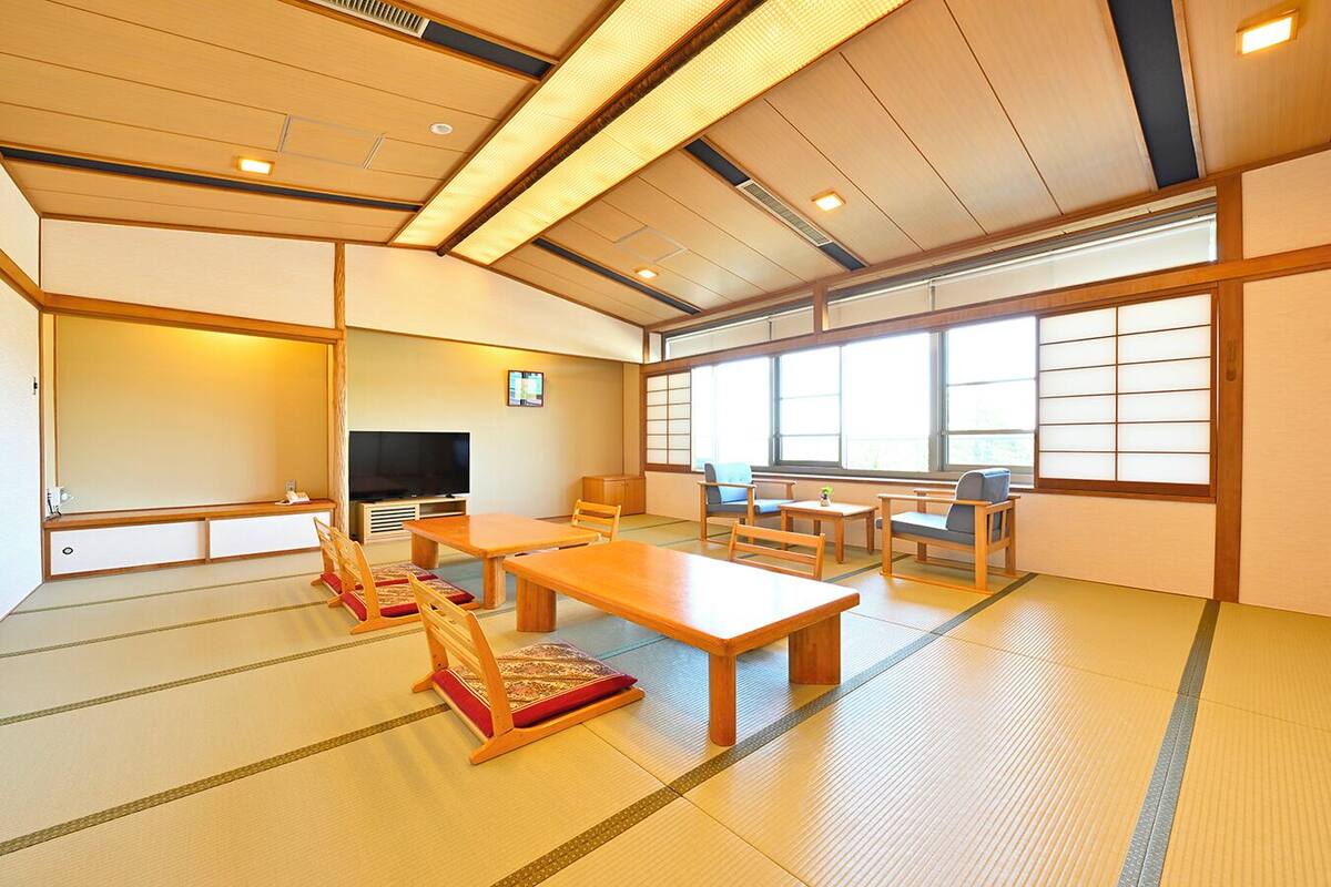 Una habitación japonesa tradicional con suelo de tatami, televisor y puertas correderas.