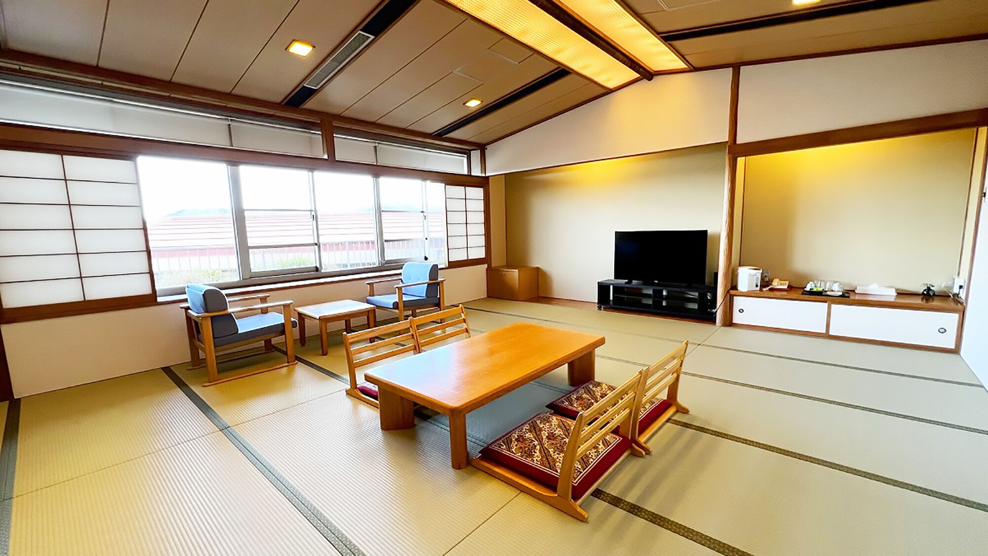 A traditional Japanese-style room with tatami flooring, a low wooden table, and a television.