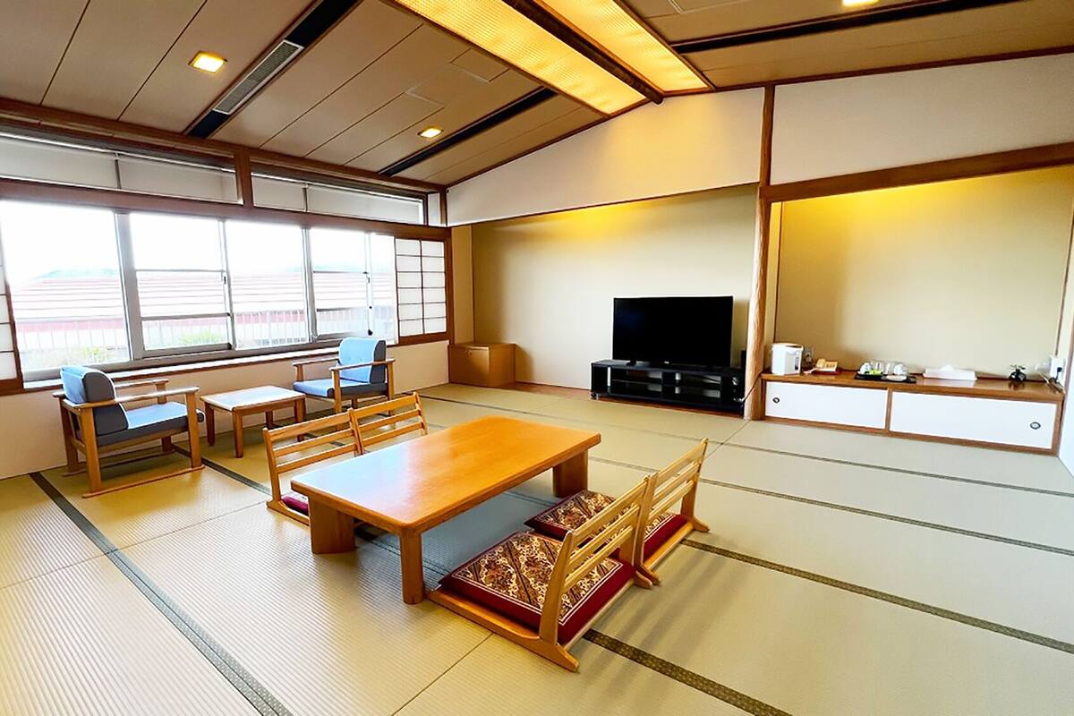 Una habitación tradicional japonesa con suelo de tatami, una mesa de madera baja y un televisor.