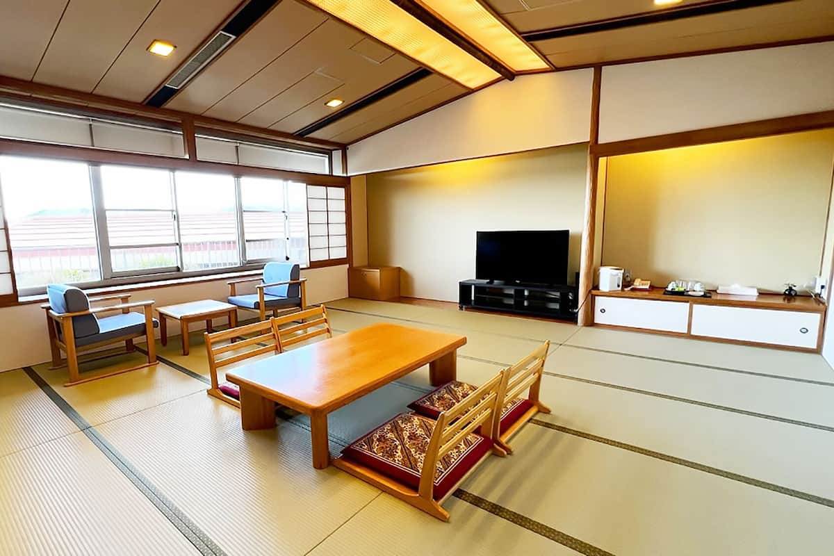 A traditional Japanese-style room with tatami flooring, a low wooden table, and a television.