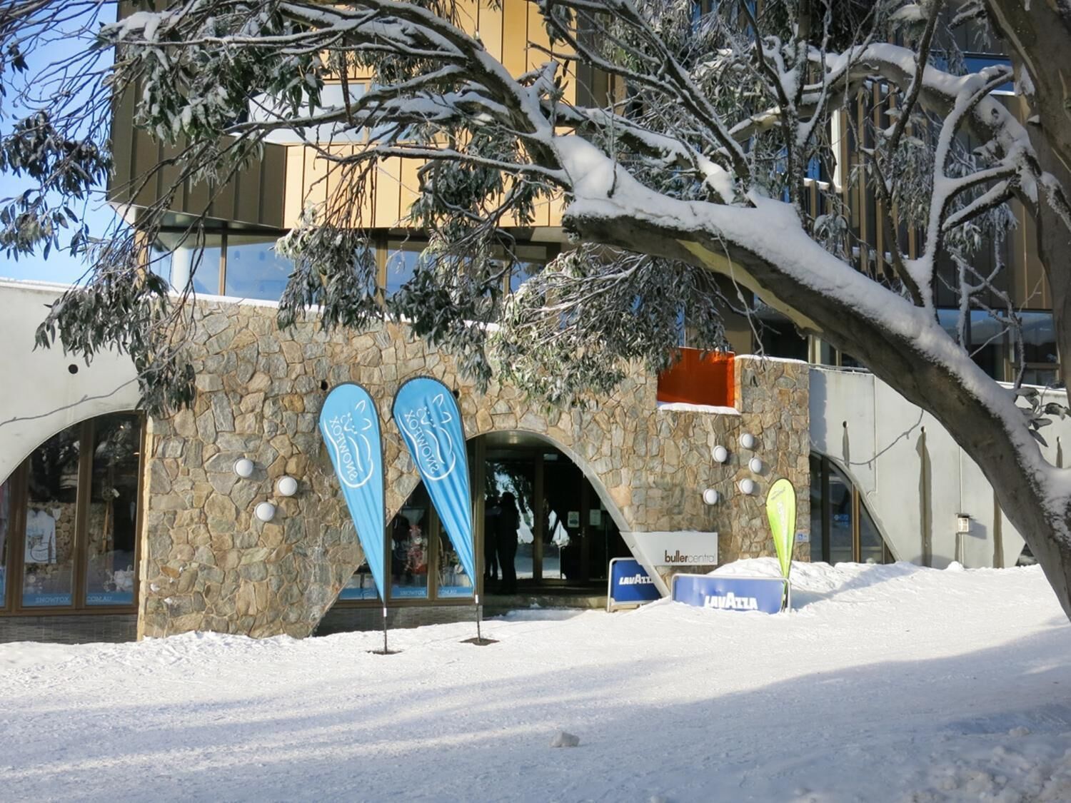 Un bâtiment en pierre dont l’entrée est recouverte de neige, avec une enseigne indiquant « Buller Central ».