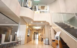 A modern interior with a curved ceiling, a staircase, and a reception desk. - Fukuoka Arty Inn (Fukuoka)