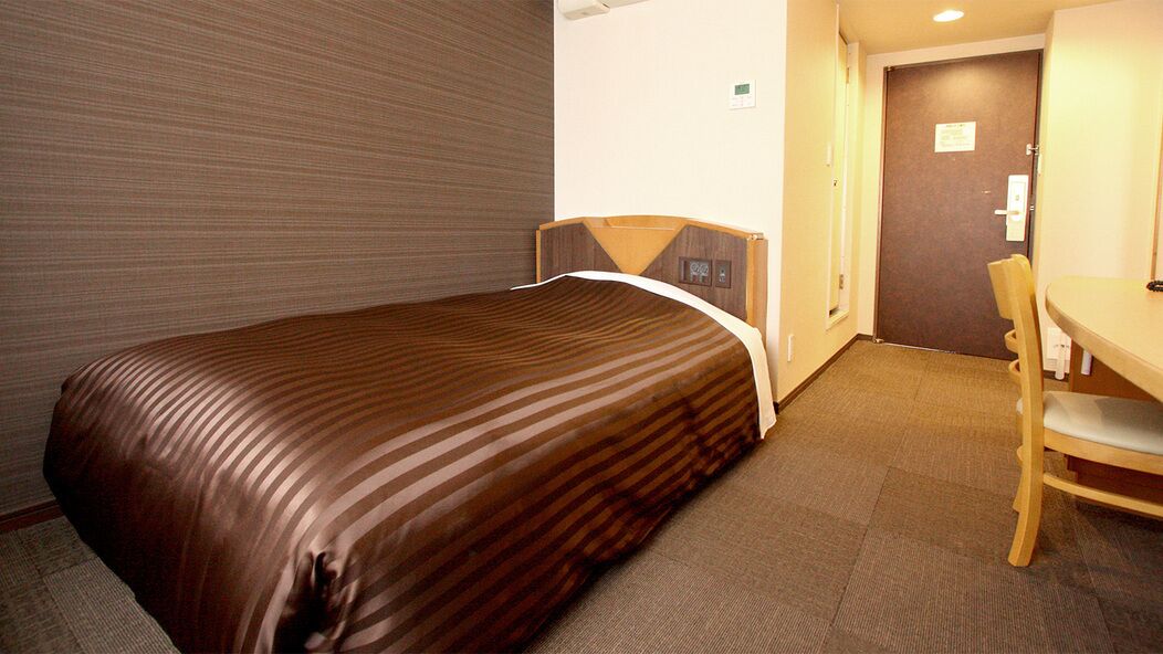 A hotel room with a bed, a desk, and a chair.