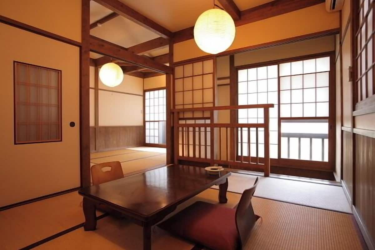 Una habitación japonesa tradicional con suelo de tatami, una mesa de madera baja y puertas correderas.