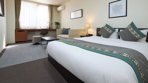 A hotel room with a large bed, a desk, a chair, a sofa, and a small table. - Hotel Tohkai (Atsugi)