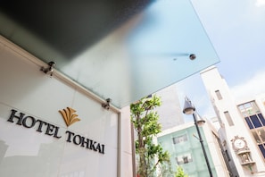 L’extérieur de l’hôtel Tohkai, avec son panneau d’identification bien visible, sa façade moderne et un lampadaire.