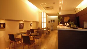 A restaurant with a counter, tables, chairs, and framed pictures on the walls. - Hotel Tohkai (Atsugi)