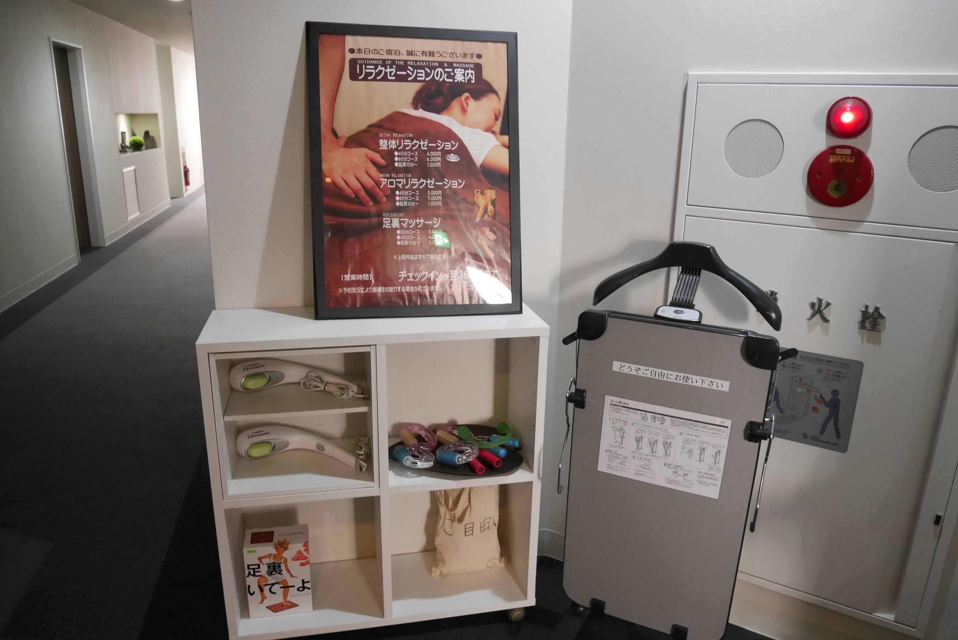 A hallway with a massage machine, a poster, and a shelf with various items.