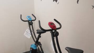 Two stationary bikes in a gym with a world map on the wall.