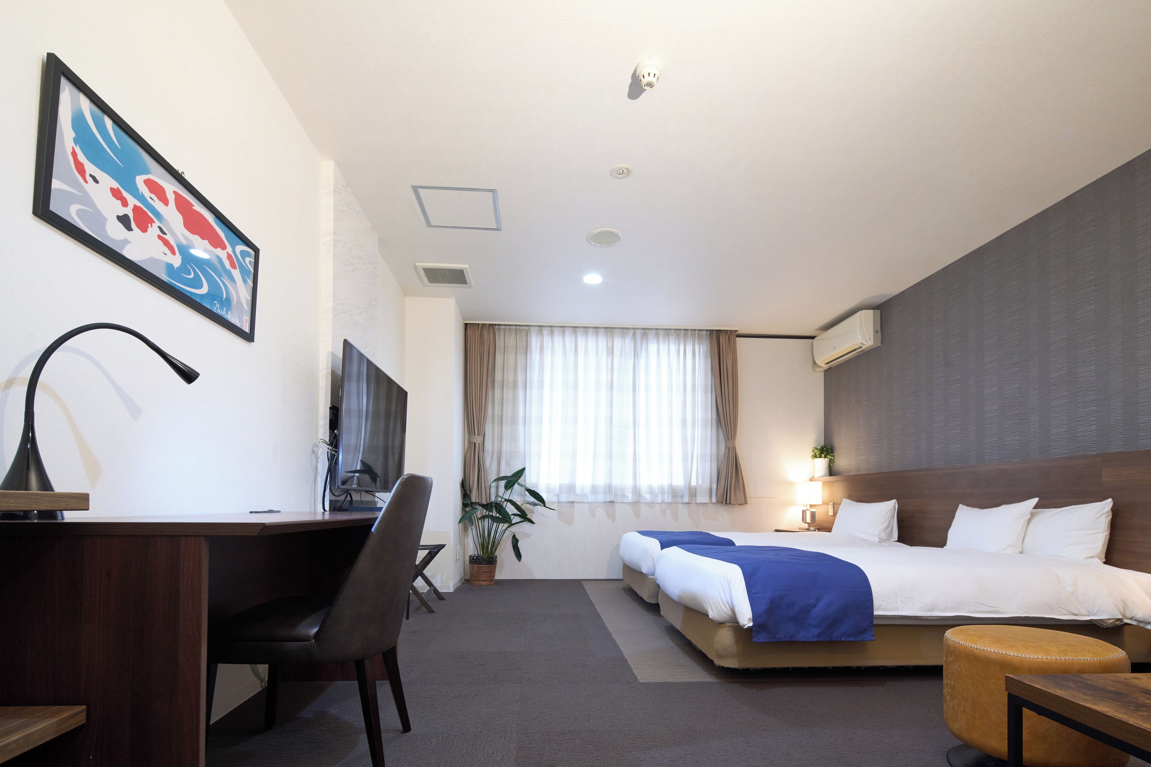 A hotel room with a desk, chair, bed, and a large window with curtains.