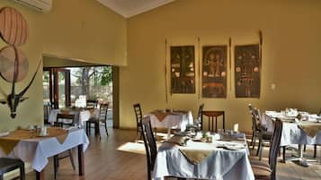 A restaurant with tables set for dining, a large window, and wall art.