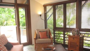A cozy room with a wicker chair, a wooden table, and a sofa. - The Wongalinga Apartments (Wongaling Beach)