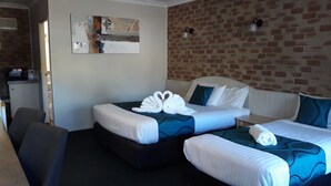 A hotel room with two beds, a brick wall, a painting, and a microwave in the corner. - Country Gardens Motor Inn Toowoomba (South Toowoomba)