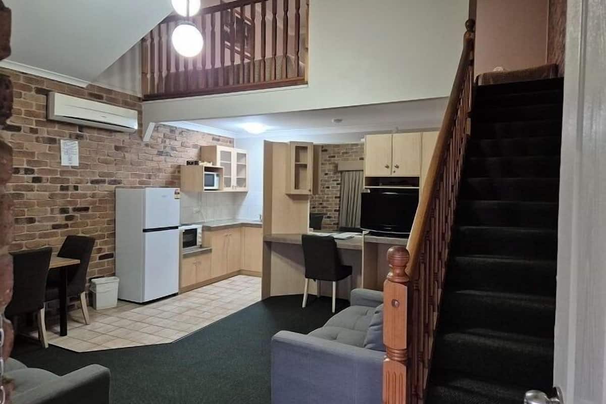 A compact living space with a kitchenette, a dining area, and a staircase leading to an upper level.