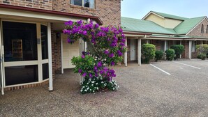 A building with a brick facade, a covered entrance, and a gravel driveway. - Country Gardens Motor Inn Toowoomba (South Toowoomba)