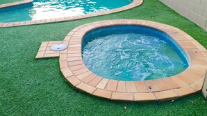 Two hot tubs with brick borders on artificial grass, surrounded by a white wall. - Country Gardens Motor Inn Toowoomba (South Toowoomba)