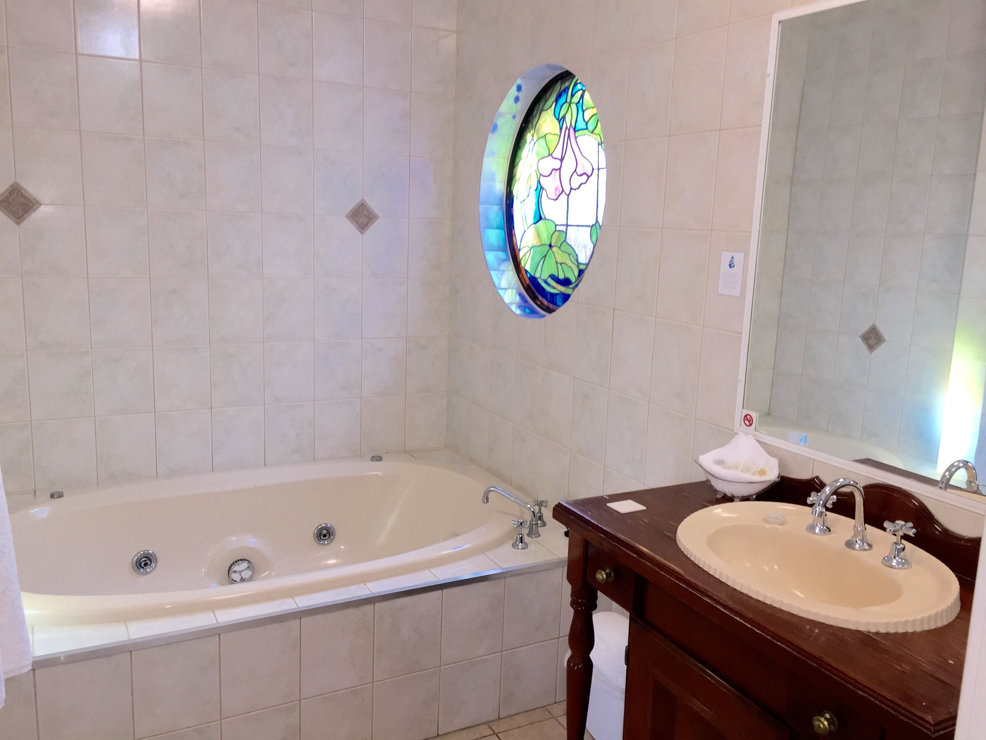 A bathroom with a large bathtub, a sink, and a mirror.